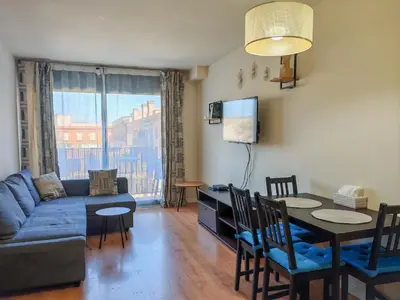 a living room with a blue couch and a dining room table at Modern Apartment near the sea in Pineda de Mar