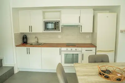 a kitchen with white cabinets and a sink and a table at Cal Rami in Castellbell i Vilar