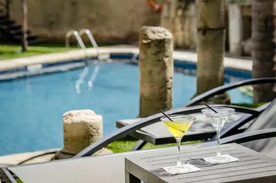 two drinks on a table next to a swimming pool at Exe Cunit Suites & Spa in Cunit
