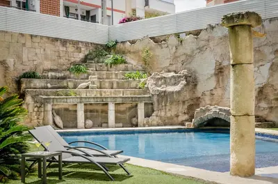 a chair and a table next to a swimming pool at Exe Cunit Suites & Spa in Cunit
