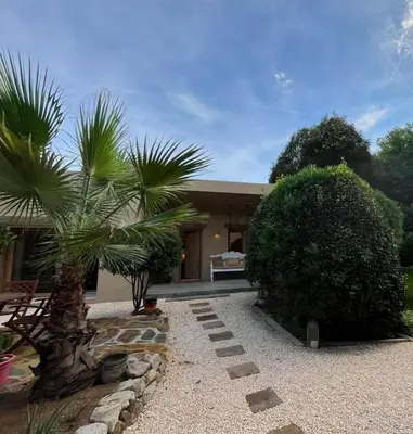 a house with a palm tree in front of it at Stylish & idyllic Finca with private garden 5 min walking from South Beach Barcelona in Gava Mar in Barcelona