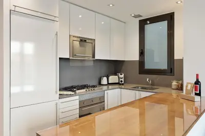 a white kitchen with white cabinets and a sink at Ola Living Viladomat in Barcelona