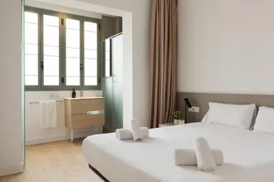 a hotel room with two beds and a bathroom at Ola Living Viladomat in Barcelona