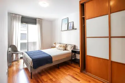 a bedroom with a bed and a desk and a window at Mai&Maud Fira Apartment in Hospitalet de Llobregat