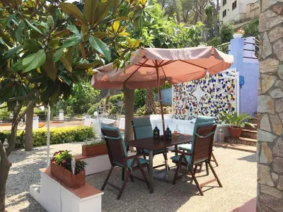 a table and chairs under an umbrella on a patio at Casa Feliz del Mar in San Pol de Mar