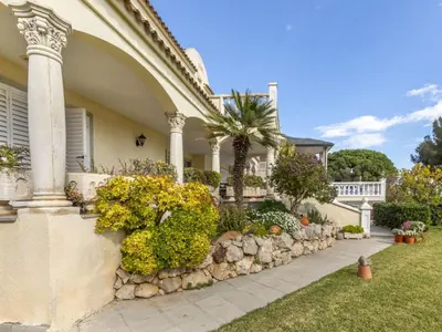 a house with a stone wall and a palm tree at Holiday Home Bon repos by Interhome in Cunit