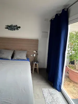 a bedroom with a bed and a blue curtain at Sitges Garden Suite in Sitges