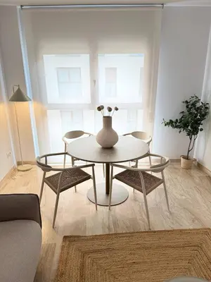 a table and chairs in a living room with a vase on it at Boutique Temporada VG Barcelona Sant Gervasi in Barcelona
