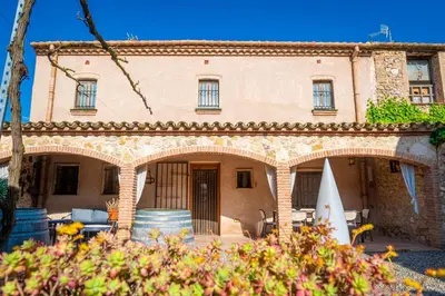 an old house with a patio and a surfboard at La Masia in Sant Pau dʼOrdal