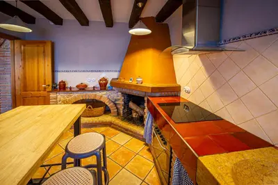 a kitchen with a stove and a stone fireplace at La Masia in Sant Pau dʼOrdal