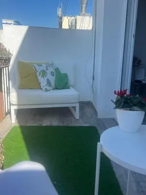 a living room with a couch and a green rug at Atico 1º linea vistas Sitges in Sitges