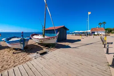 a large sign on a beach with palm trees and the ocean at Apartament in Pineda in Pineda de Mar