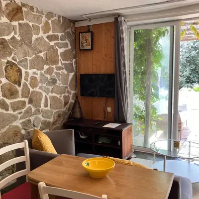a living room with a table and a stone wall at Estudio limonero en Sant Cebriá de Vallalta 20' playa in Sant Cebrià de Vallalta