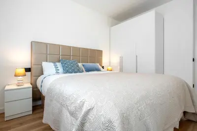 a bedroom with a large white bed with blue pillows at Hauzify I Casa Somella in Vilanova i la Geltrú