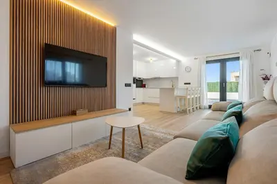 a living room with a couch and a tv on a wall at Hauzify I Casa Somella in Vilanova i la Geltrú