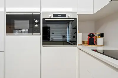 a kitchen with white cabinets and a stove top oven at Hauzify I Casa Somella in Vilanova i la Geltrú