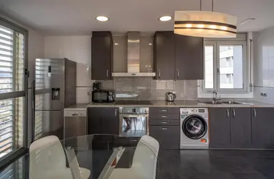 a kitchen with a washing machine and a glass table at Av d'Eduard Maristany, 13 in Sant Adria de Besos