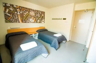 two beds in a small room with a painting on the wall at Barcelona Pere Tarrés Youth Hostel in Barcelona