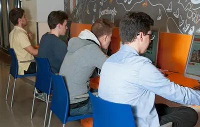 a group of men sitting at a table looking at a computer at Barcelona Pere Tarrés Youth Hostel in Barcelona