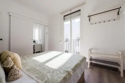 a white bedroom with a bed and a large window at Precioso apartamento en Ronda Sant Pau in Barcelona