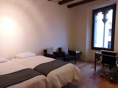 a bedroom with two beds and a desk and a window at Beautiful 15th century villa on 30 acre estate, for families only in Alella