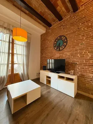 a living room with a clock on a brick wall at Centric 2 Bedroom Apartment in Barcelona