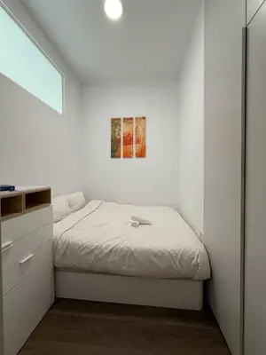 a white bedroom with a bed and a painting on the wall at Centric 2 Bedroom Apartment in Barcelona