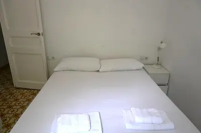a white bed in a room with two towels on it at Homenfun Barcelona Sants Estación in Barcelona