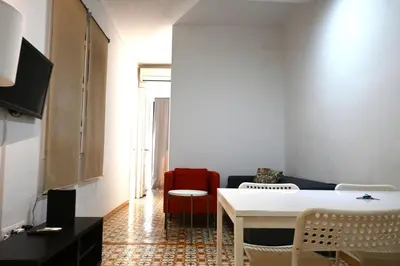 a living room with a white table and a red chair at Homenfun Barcelona Sants Estación in Barcelona