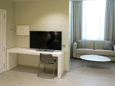 a living room with a couch and a desk with a television at Serennia Exclusive Rooms in Barcelona