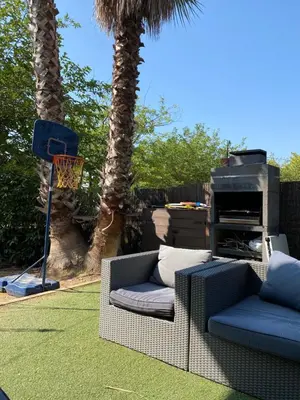 a patio with two chairs and a grill and palm trees at Apartamento 3 habitaciones con piscina in Sant Cugat del Vallès