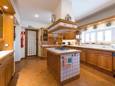 a large kitchen with wooden cabinets and a large island at Cal Tomas in Castellet
