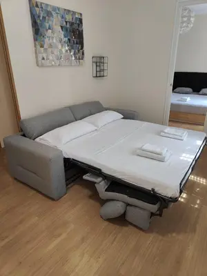 a bed sitting in a room with a couch at Elegant apartment Rambla Badal in Barcelona