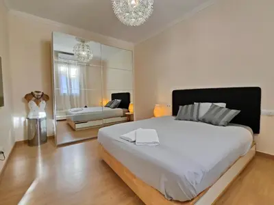 a bedroom with a large white bed and a mirror at Elegant apartment Rambla Badal in Barcelona