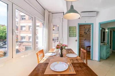 a dining room with a table and chairs and windows at 1º Apartamento 3 hab 15' Barcelona centro 8' Playa in Sant Adria de Besos