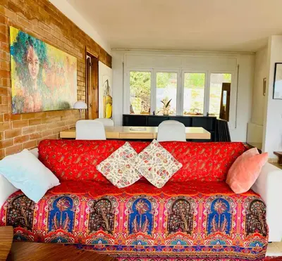a living room with a red couch with pillows at CAN FENICIA - 30 min to F1 & MotoGP - Intimate Villa, Private Pool & Sea View in Arenys de Munt
