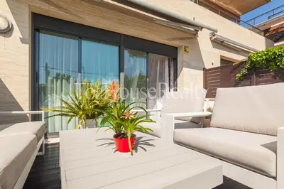 a patio with white chairs and a table with plants at La Pineda in Castelldefels