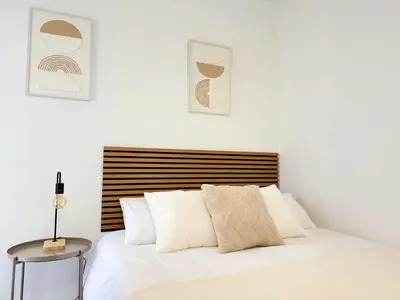 a bedroom with a white bed with a wooden headboard at Atico frente al mar! in Gavà
