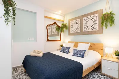 a bedroom with a bed with blue pillows and a mirror at Estudios a 10' caminando de la playa y a 20' de Barcelona Centro in Sant Adria de Besos