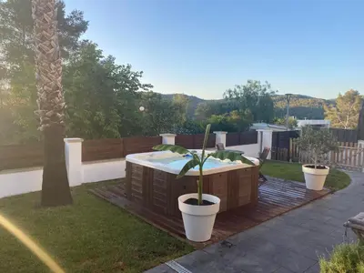 a hot tub on a deck with a palm tree at Apartamento a 5 minutos de Sitges in Sant Pere de Ribes