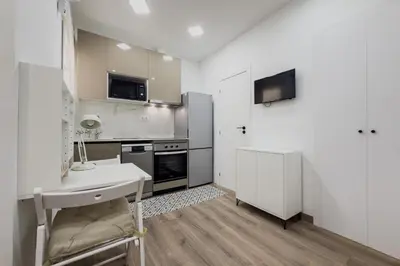 a kitchen with white cabinets and a table and a sink at Bonito Apartamento en Ronda Sant Pau in Barcelona