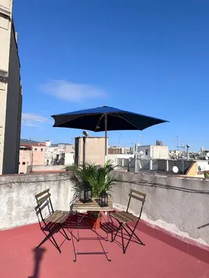 two chairs and a table with an umbrella on a roof at Bonito Apartamento en Ronda Sant Pau in Barcelona