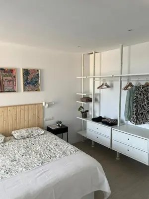 a bedroom with a bed and a dresser and shelves at Artistic beach apartment in Cunit
