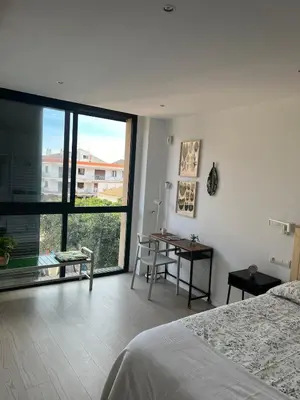 a bedroom with a bed and a table and a window at Artistic beach apartment in Cunit