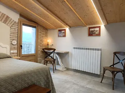 a bedroom with a bed and a radiator and a window at El Freixe de l'Ylla in Els Hostalets