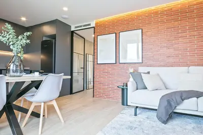 a living room with a white couch and a brick wall at Joan Austria 2 Bedroom Apartment in Barcelona