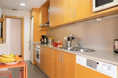 a kitchen with wooden cabinets and a sink and a bowl of fruit at Lets Holidays Terrace Barcelona in Barcelona
