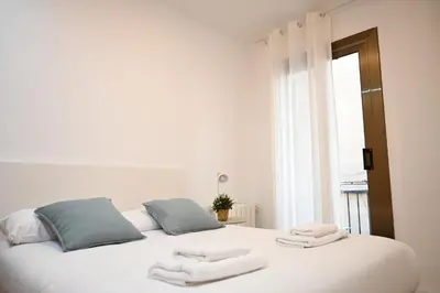 a bedroom with a white bed with towels on it at Homenfun Barcelona Avenida Diagonal in Barcelona
