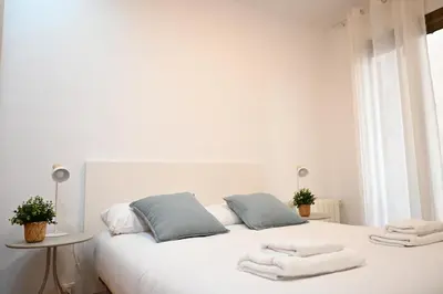 a white bedroom with a white bed with towels on it at Homenfun Barcelona Avenida Diagonal in Barcelona