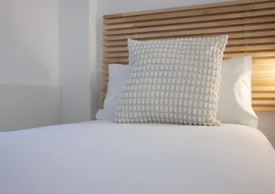 a white bed with a pillow on top of it at Stay U-nique Apartments Villarroel II in Barcelona